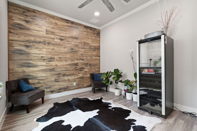 living area with ceiling fan, wood-type flooring, and ornamental molding