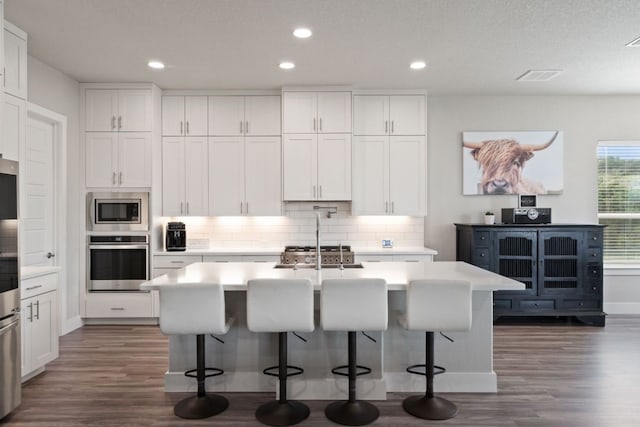 kitchen featuring a center island with sink, white cabinets, and appliances with stainless steel finishes