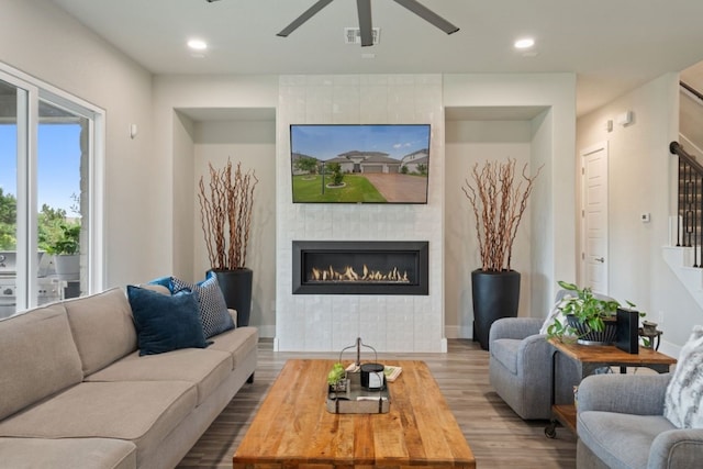 living room featuring a fireplace, wood-type flooring, and ceiling fan