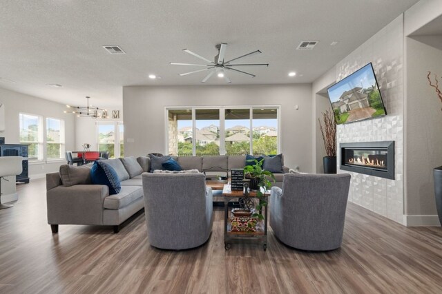 living room featuring a textured ceiling, ceiling fan with notable chandelier, and hardwood / wood-style flooring