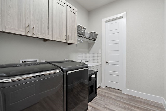 laundry area featuring cabinets, light hardwood / wood-style flooring, washer and dryer, and sink