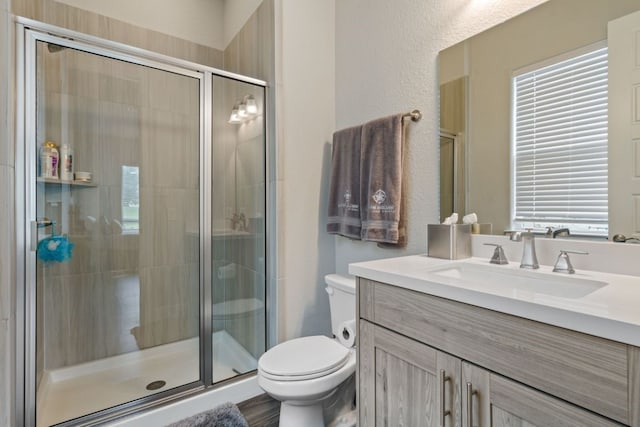 bathroom featuring vanity, a shower with shower door, and toilet