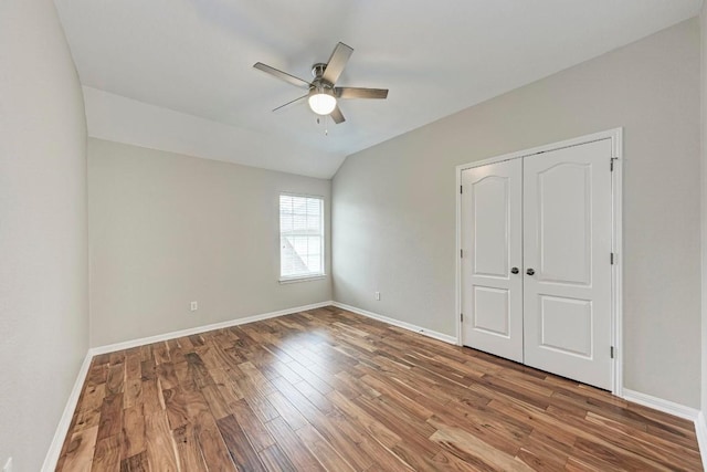 unfurnished bedroom featuring hardwood / wood-style floors, a closet, ceiling fan, and lofted ceiling