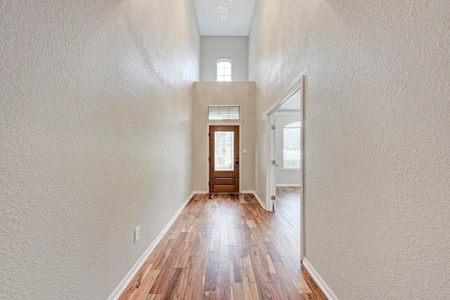 entryway featuring hardwood / wood-style flooring, a towering ceiling, and a chandelier