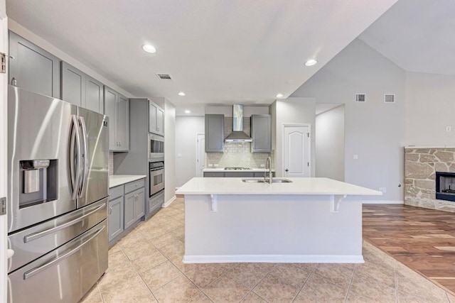 kitchen featuring sink, stainless steel appliances, gray cabinets, and wall chimney range hood