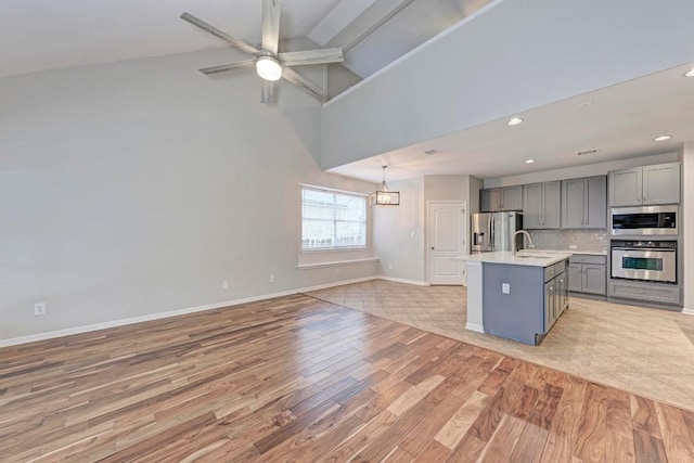 kitchen with pendant lighting, a kitchen island with sink, gray cabinets, tasteful backsplash, and stainless steel appliances