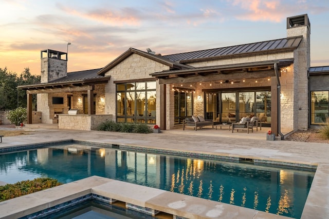 exterior space with an outdoor living space with a fireplace, a patio, and a pool with hot tub