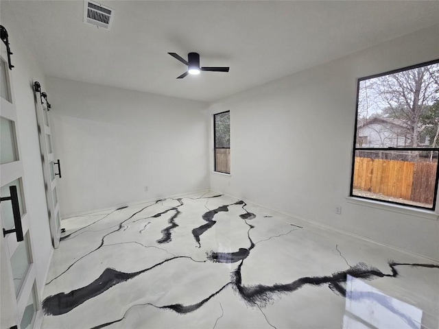 spare room featuring a barn door and ceiling fan