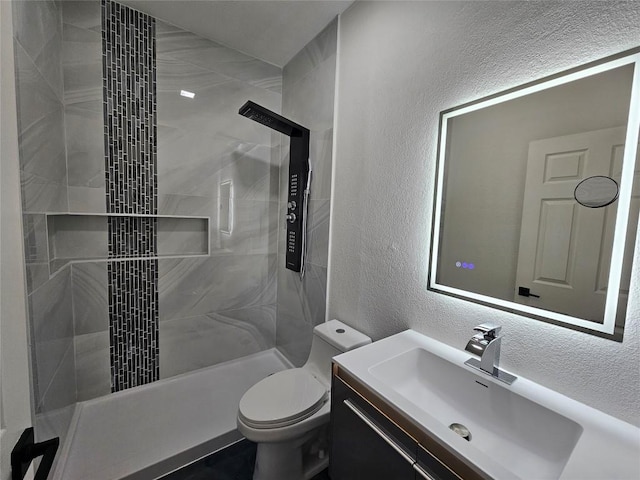 bathroom featuring toilet, vanity, and tiled shower