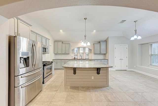 kitchen featuring gray cabinetry, light stone countertops, a center island, stainless steel appliances, and a notable chandelier