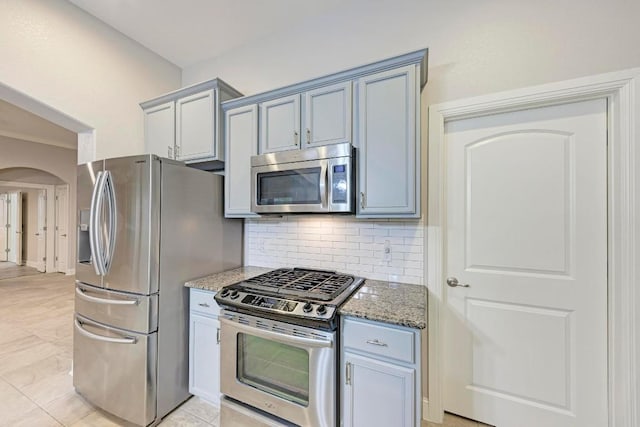 kitchen with decorative backsplash, light tile patterned floors, stainless steel appliances, and stone countertops