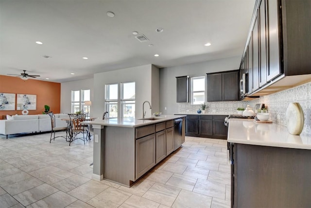 kitchen with tasteful backsplash, dark brown cabinetry, sink, a center island with sink, and dishwasher