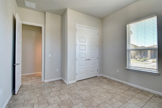 unfurnished bedroom with light tile patterned floors, multiple windows, and a closet