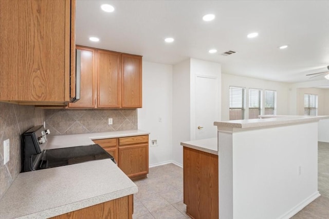 kitchen with backsplash, stainless steel electric stove, ceiling fan, light tile patterned floors, and kitchen peninsula