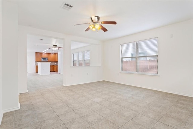 tiled empty room featuring ceiling fan