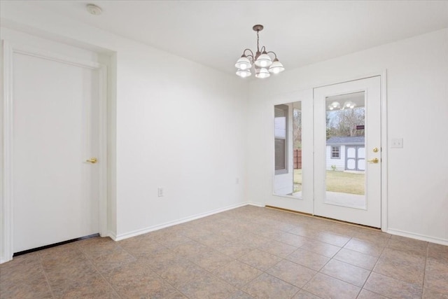 tiled spare room featuring an inviting chandelier