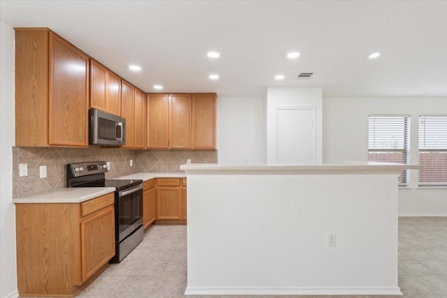 kitchen featuring a kitchen island, light tile patterned flooring, stainless steel appliances, and tasteful backsplash