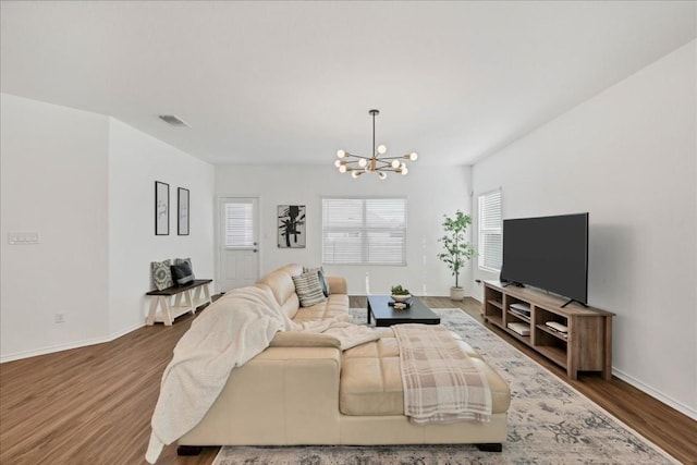 living room with baseboards, a notable chandelier, visible vents, and dark wood-style flooring