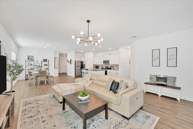 living area featuring a chandelier, light wood-type flooring, visible vents, and recessed lighting