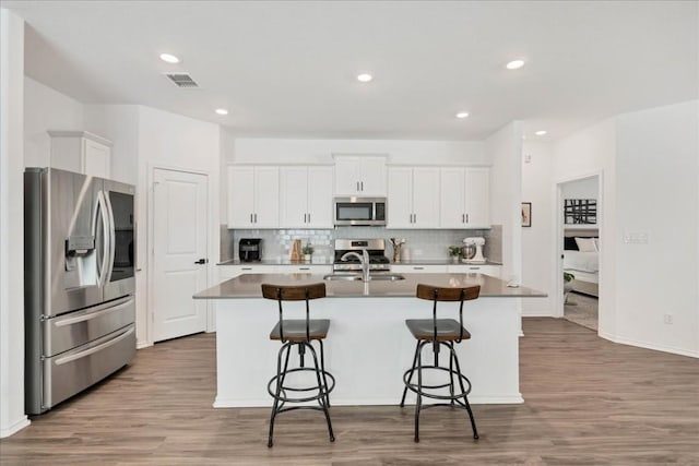 kitchen with a breakfast bar area, visible vents, appliances with stainless steel finishes, a sink, and an island with sink