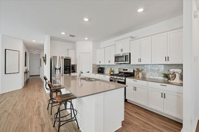 kitchen with a center island with sink, white cabinetry, sink, and appliances with stainless steel finishes