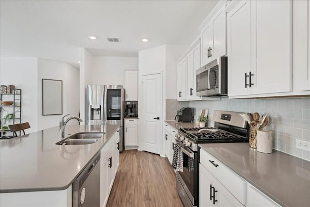 kitchen featuring decorative backsplash, stainless steel appliances, white cabinetry, and sink