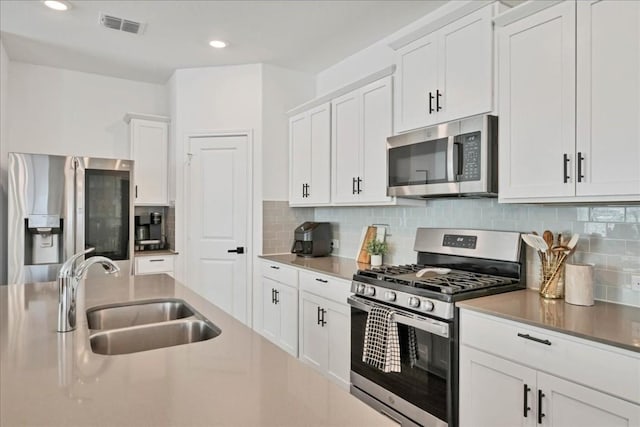 kitchen featuring appliances with stainless steel finishes, white cabinetry, and sink