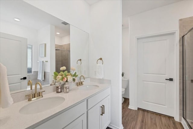 bathroom with hardwood / wood-style floors, an enclosed shower, and toilet