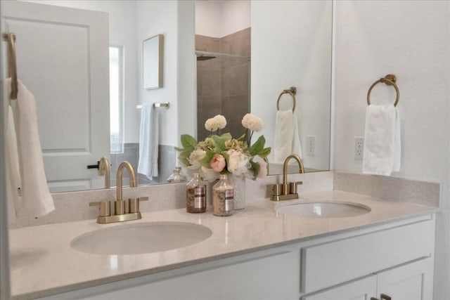 bathroom with double vanity, a shower stall, and a sink