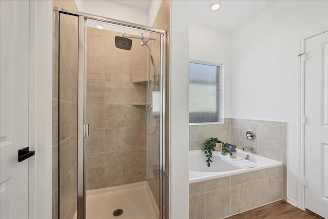 full bath featuring a garden tub, a shower stall, and wood finished floors