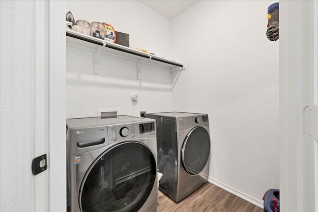 clothes washing area featuring laundry area, light wood finished floors, independent washer and dryer, and baseboards