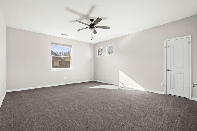 unfurnished room with ceiling fan and dark carpet