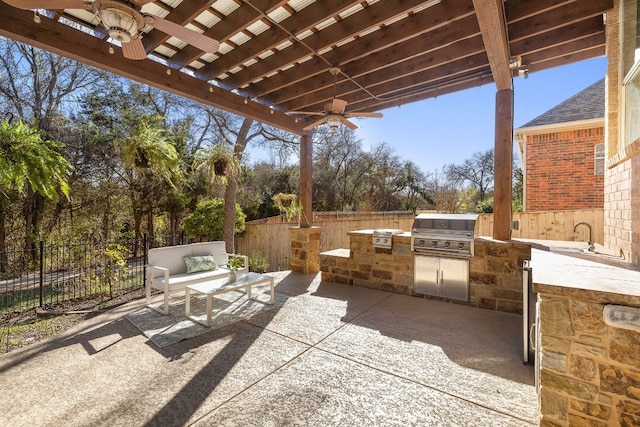 view of patio with an outdoor living space, a grill, ceiling fan, and exterior kitchen