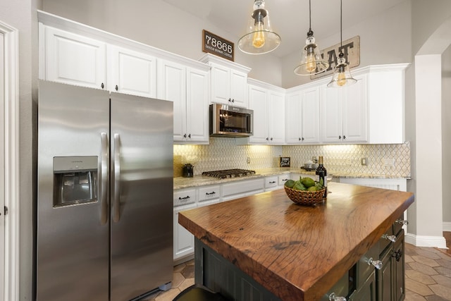 kitchen featuring white cabinets, stainless steel appliances, a kitchen island, and hanging light fixtures