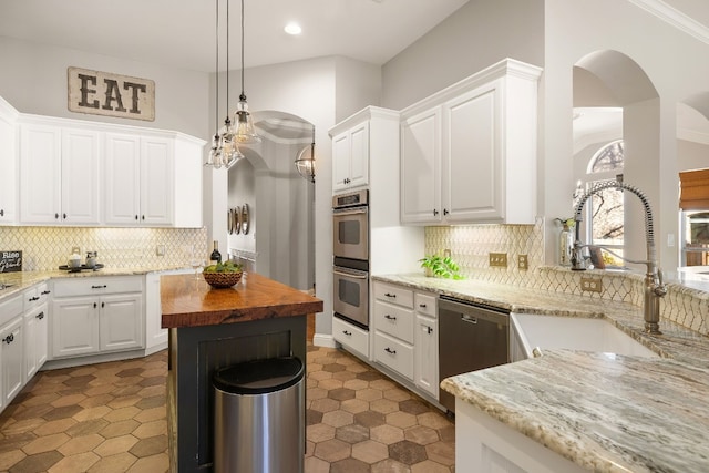 kitchen with light stone countertops, sink, decorative light fixtures, white cabinets, and appliances with stainless steel finishes