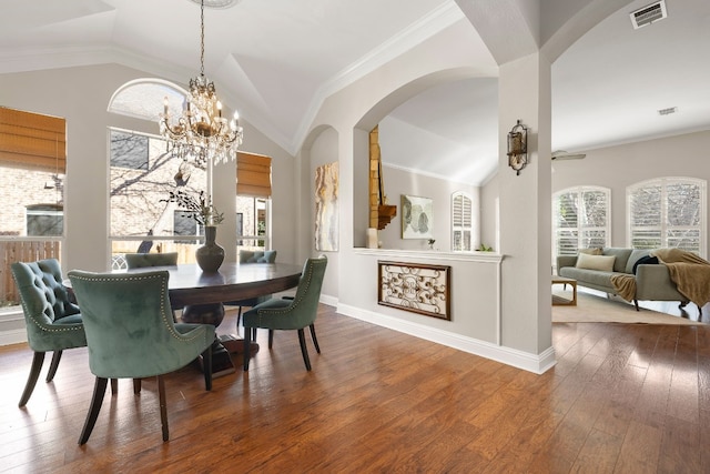 dining area featuring a chandelier, wood-type flooring, crown molding, and lofted ceiling