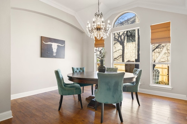 dining room featuring hardwood / wood-style flooring, a notable chandelier, a wealth of natural light, and vaulted ceiling