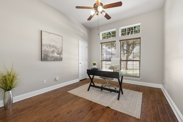 office featuring a towering ceiling, ceiling fan, and dark wood-type flooring