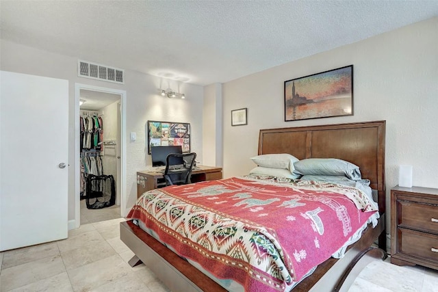 bedroom featuring a textured ceiling, a spacious closet, and a closet