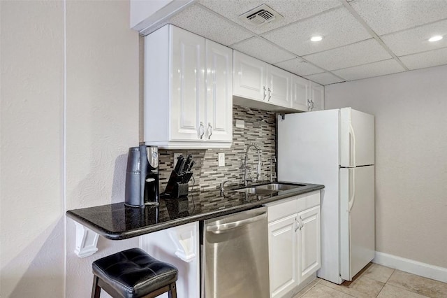 kitchen featuring white cabinetry, sink, tasteful backsplash, stainless steel dishwasher, and a breakfast bar area