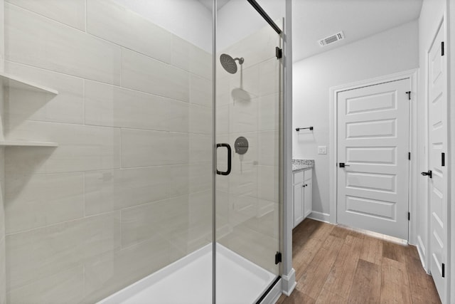 bathroom featuring vanity, wood-type flooring, and walk in shower