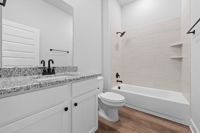 full bathroom featuring hardwood / wood-style flooring, tiled shower / bath, vanity, and toilet