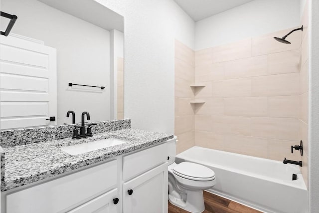 full bathroom with tiled shower / bath combo, vanity, hardwood / wood-style floors, and toilet