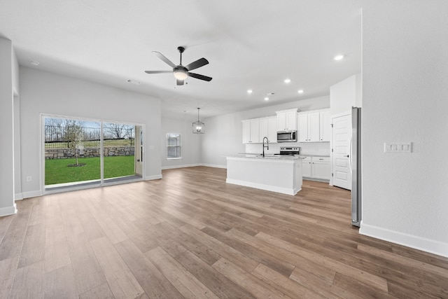 unfurnished living room with light hardwood / wood-style floors, ceiling fan, and sink