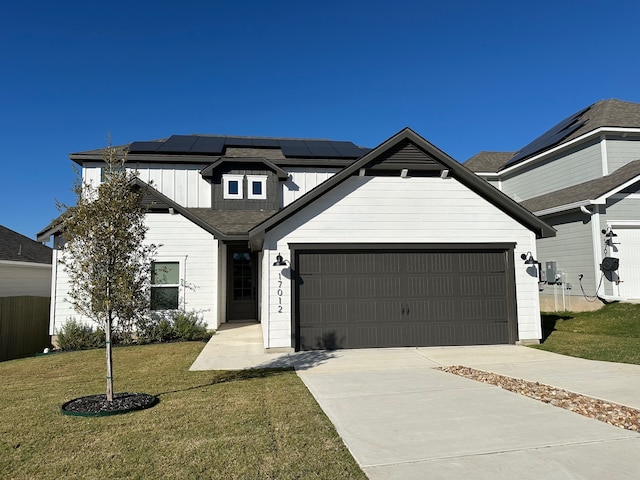 view of front of home with a garage, a front lawn, and solar panels