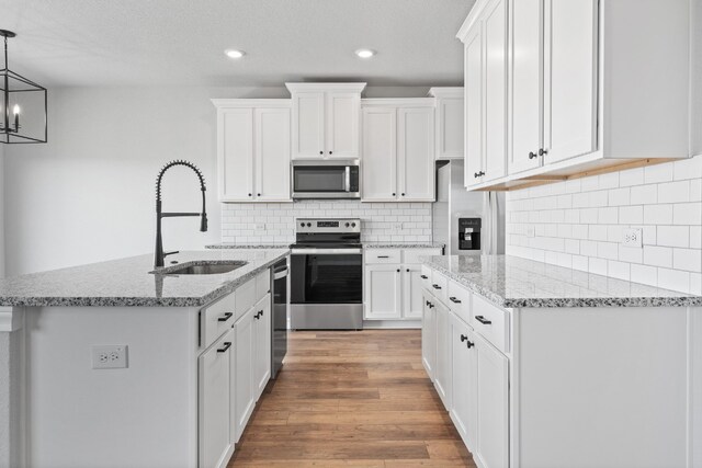 kitchen with white cabinets, decorative light fixtures, sink, and appliances with stainless steel finishes