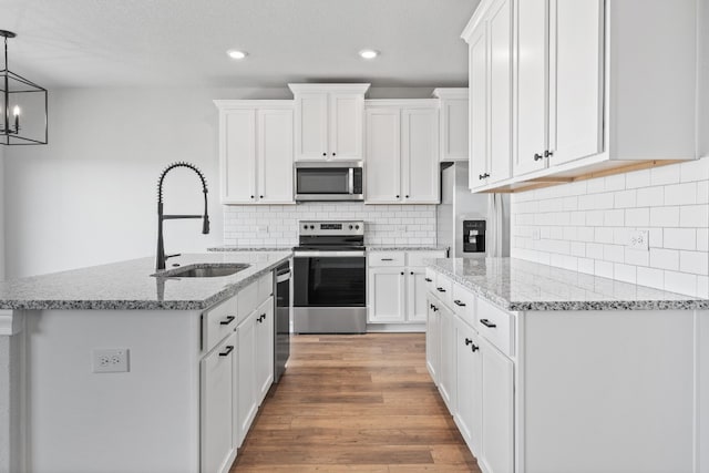 kitchen featuring white cabinetry, stainless steel appliances, sink, and pendant lighting