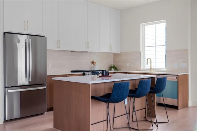 kitchen featuring white cabinets, stainless steel appliances, a kitchen island, and sink