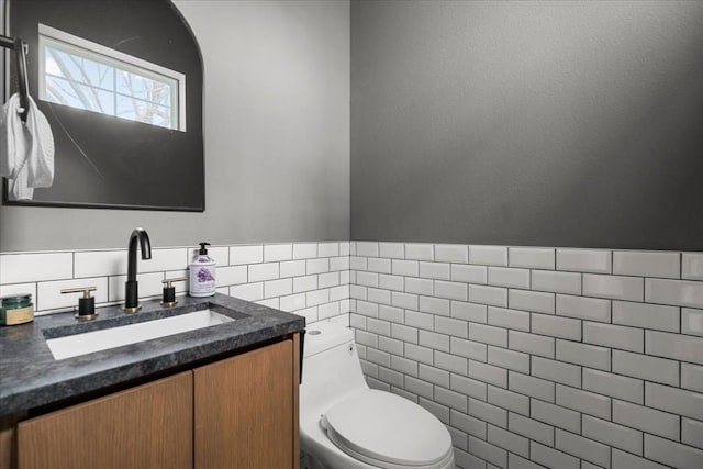 bathroom with vanity, toilet, and tile walls