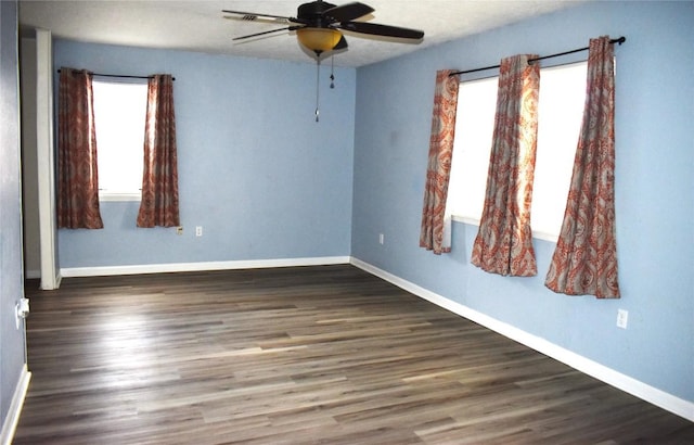 spare room with ceiling fan, a healthy amount of sunlight, and dark hardwood / wood-style flooring